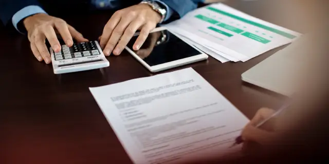 closeup-insurance-agent-making-calculations-while-signing-agreement-with-client-office.webp